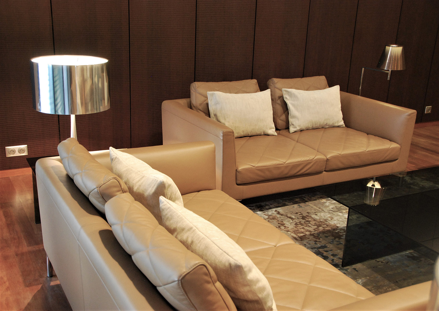 Salon VIP avec canapés De Sede DS-48/03 en cuir Nougat, tapis en soie végétale et luminaires sur fond de murs en placage bois façon Croco.