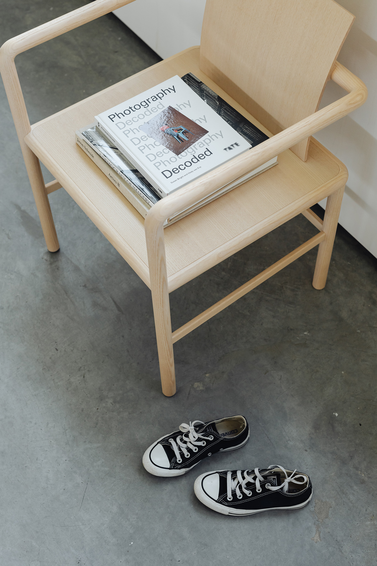 Fauteuil en bois clair sur sol en béton ciré.