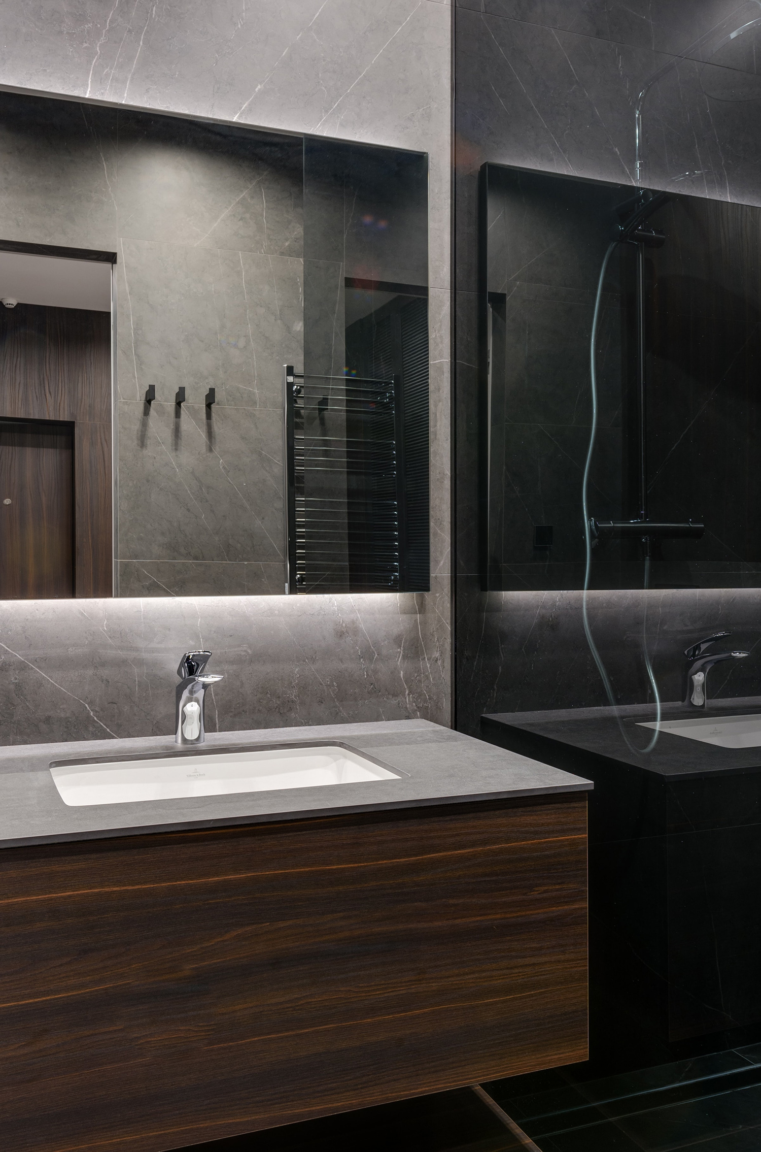 Salle de bain avec meuble vasque en bois et carrelage gris chaud aux nuances minérales.
