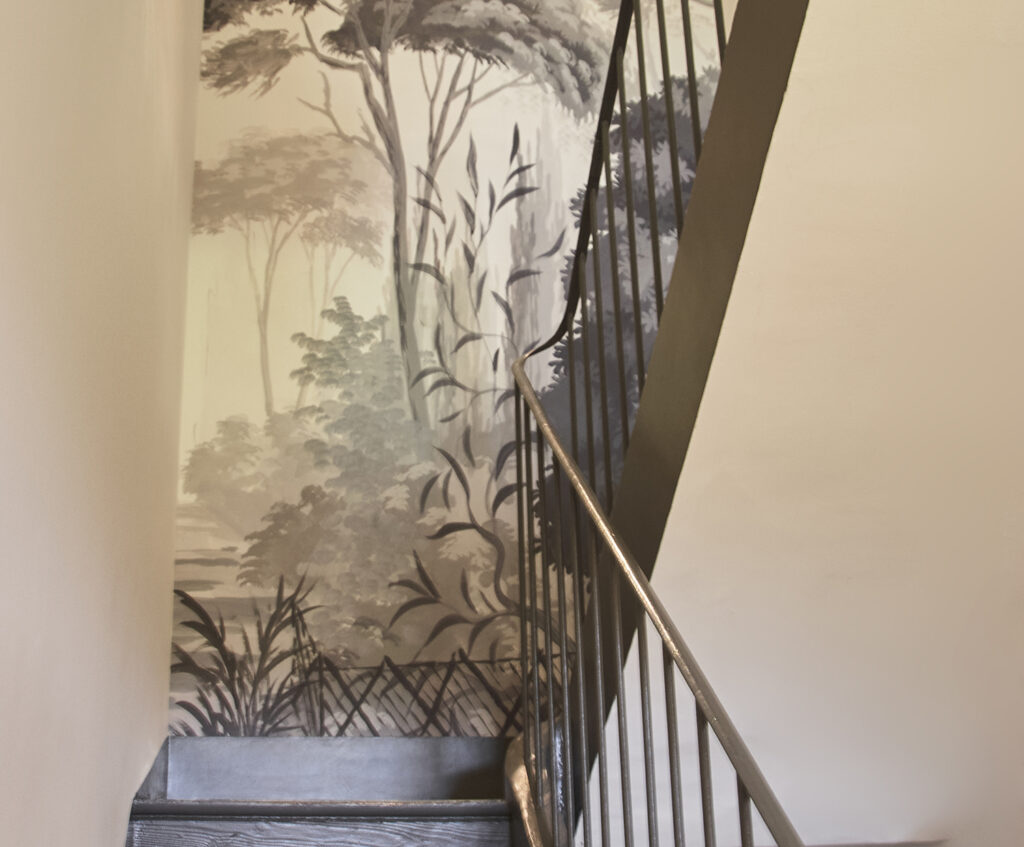 Escalier avec garde-corps gris graphite et papier peint panoramique Ananbô dans un mas ancien.
