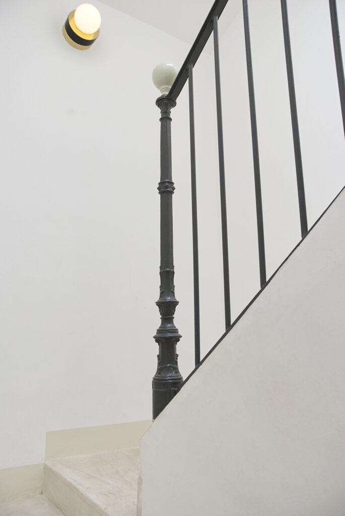 Escalier aux marches en béton ciré et garde-corps en ferronnerie d'origine.